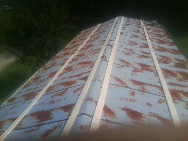 Rusted metal roof panels with new wood purlins before replacement — Storm Damage Roof Repair in Red Cliff by Roofing Brothers