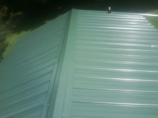 New green metal panels meeting at the ridge of a roof — Flat Roof Repair work by our crew in Red Cliff