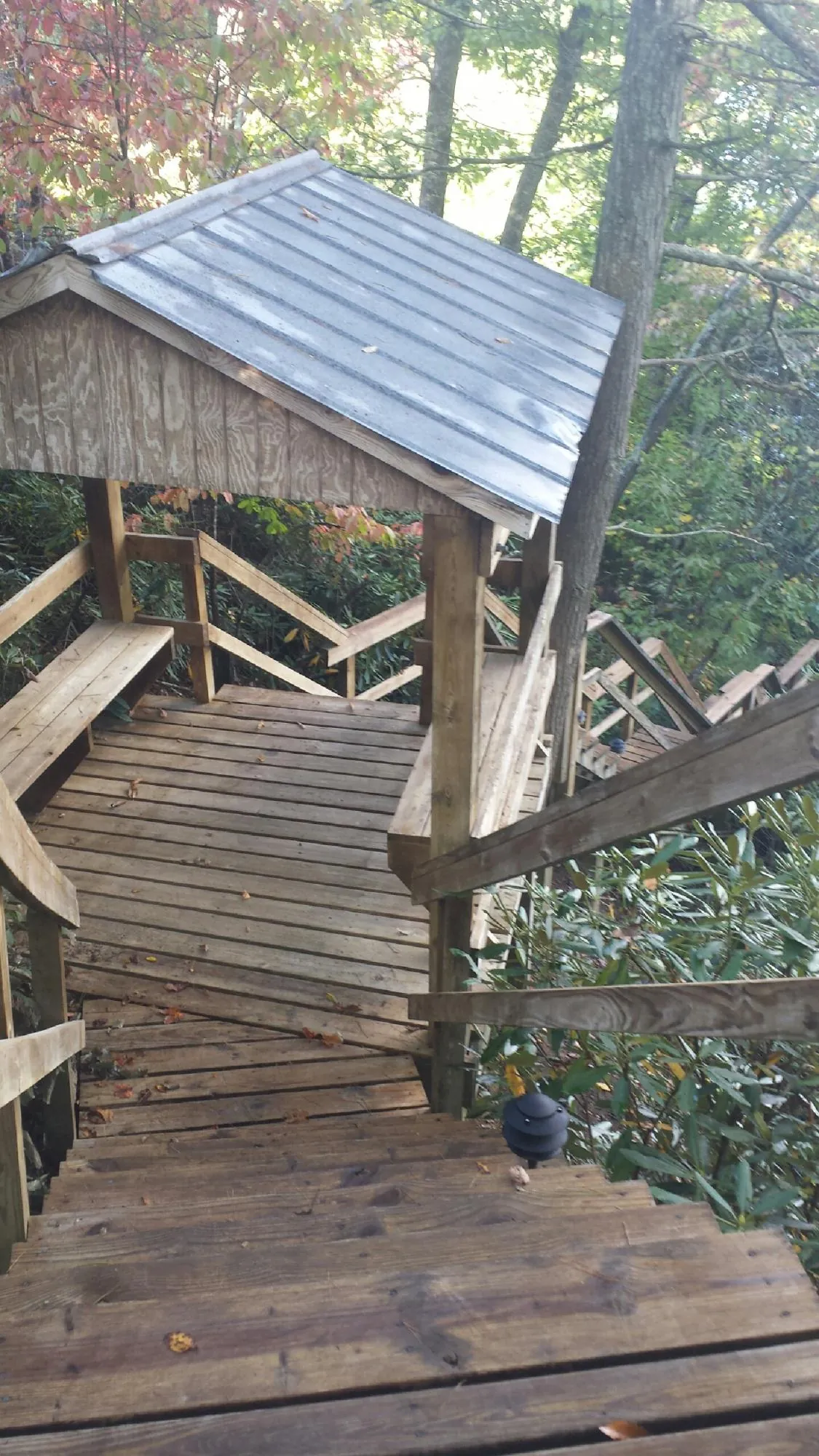 Metal roofed shelter over wooden steps on a wooded walkway — Skylight Repair & Installation work by our crew in Red Cliff
