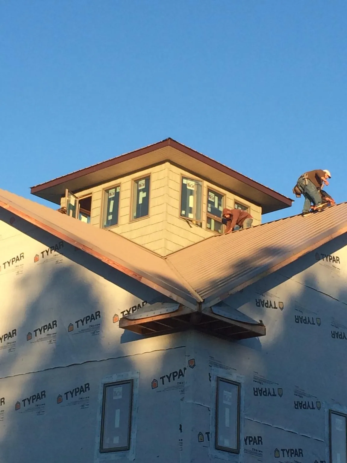 Roofers working around a rooftop cupola on a new metal roof at sunset — Roof Waterproofing in Red Cliff by Roofing Brothers
